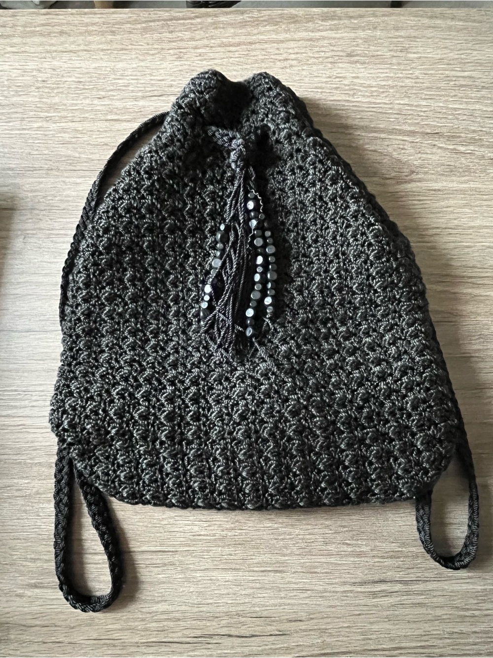 The SAK Black Lined Crochet Drawstring Backpack Purse Bag with Beaded Tassel